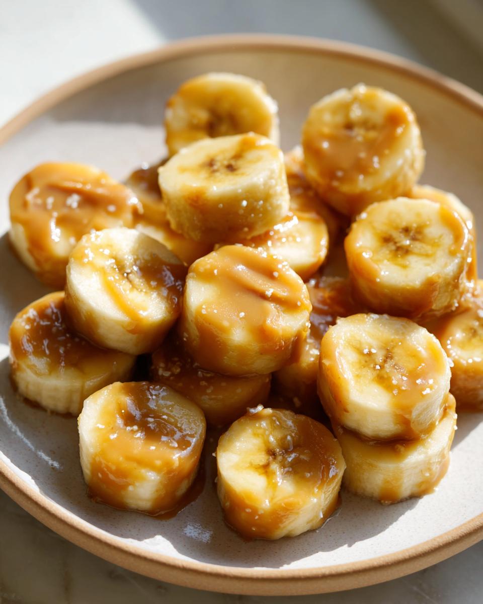 Close-up of sliced bananas drizzled with peanut butter, forming Easy 2-Ingredient Frozen Banana PB Bites for Dogs.