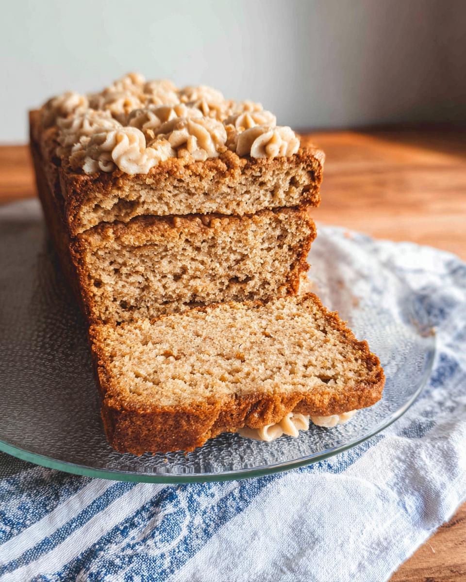 A thick slice cut from a Soft PB Banana Dog Loaf Cake, showing the moist crumb and peanut butter frosting swirls.