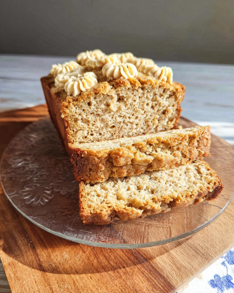 A loaf of Soft PB Banana Dog Loaf Cake, sliced, showing its texture and peanut butter frosting dollops.