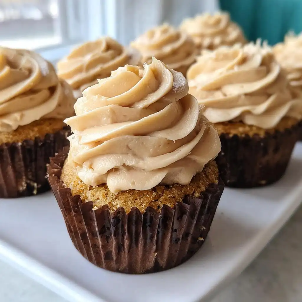 A close-up of one of the Peanut Butter Pupcakes with Fluffy Frosting, featuring a tall swirl of tan frosting.